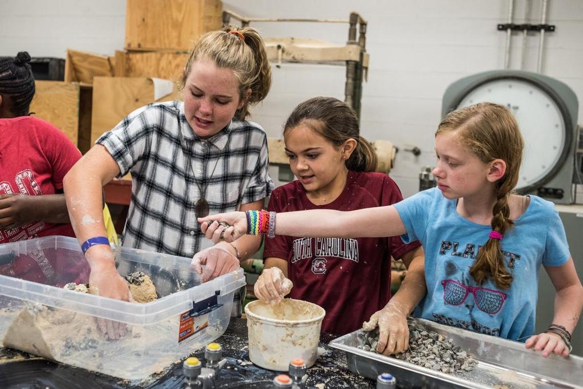 Anne Stewart, Maggie Leventis and Martha Noble work together to construct a bridge out of rocks, clay, and sand during an engineering camp last year at the University of South Carolina.