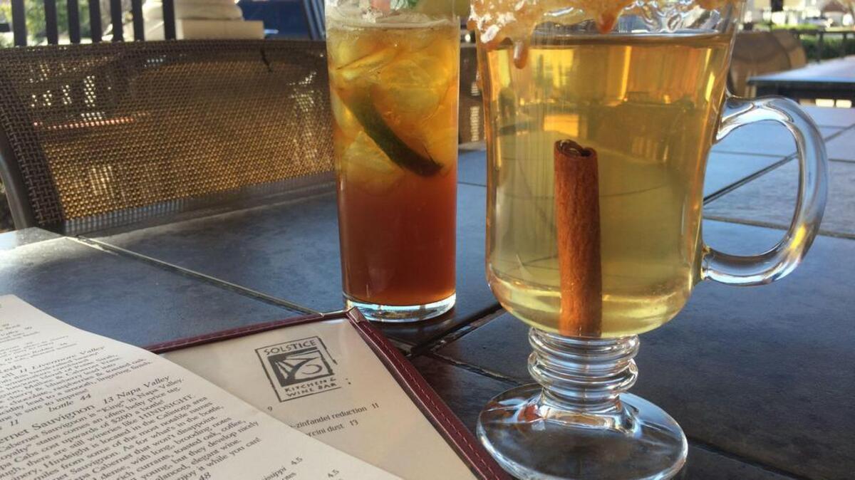Solstice Kitchen: Holiday cocktails include Candied Apple-Ginger Fizz, left, and Uncle Ricky’s Spiked Cider. Pair the Fizz with the artisan cheese plate and the cider with the apple bacon Gruyere flatbread.