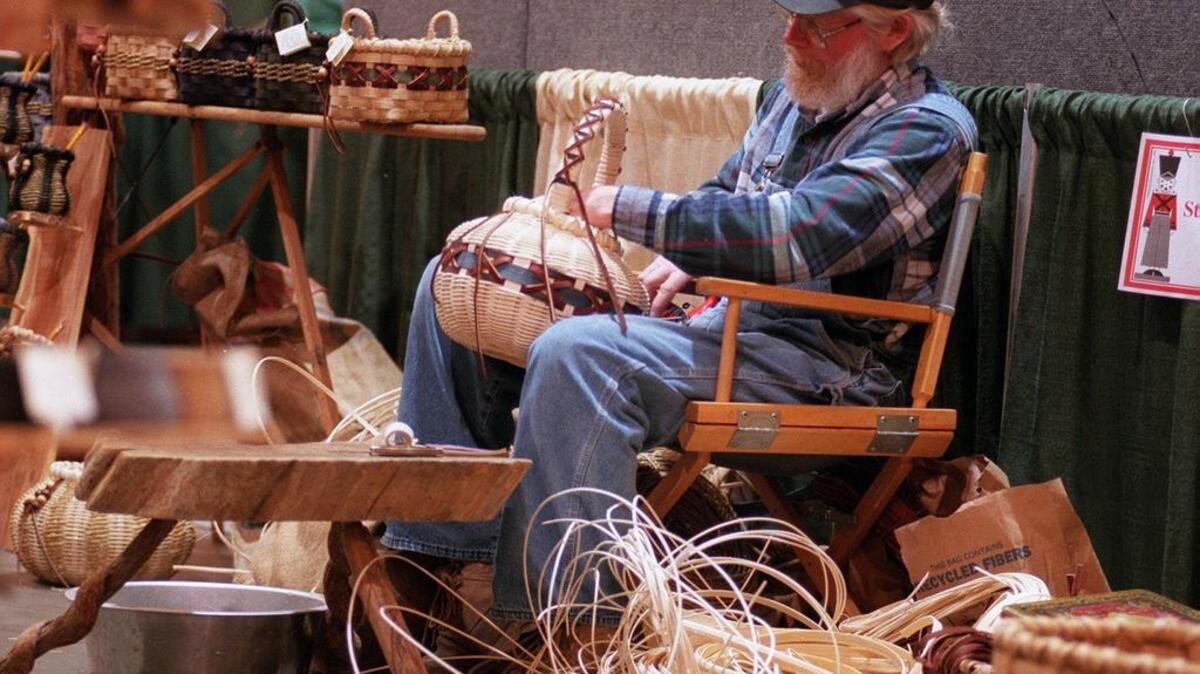An artist works on an apple basket made of reed with leather accents during a past Craftsmen’s Classic event.