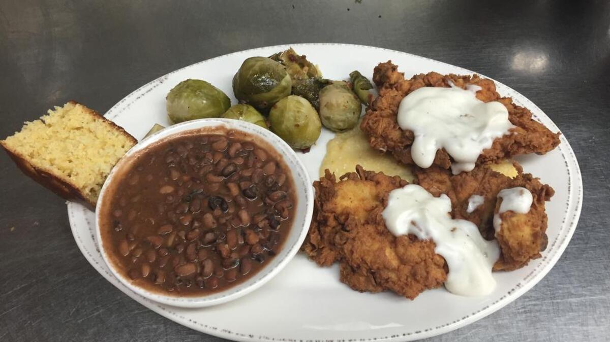 Buttermilk fried chicken is served over Keisler’s Mill yellow grits, with Sea Island red peas, roasted brussels sprouts and housemade cornbread.