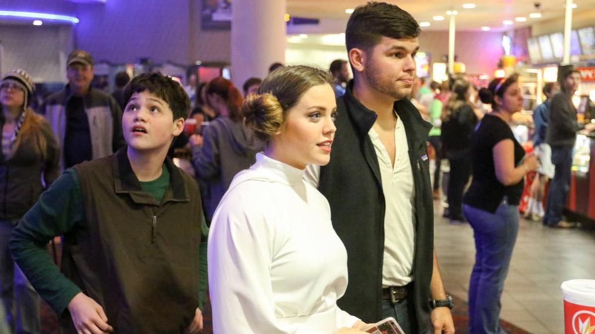 Landon McAfee, Rachel McAfee, dressed as Princess Leia, and Thomas Awtrey, dressed as Han Solo, wait in line to enter the theater on the opening night of “Star Wars: The Force Awakens.”