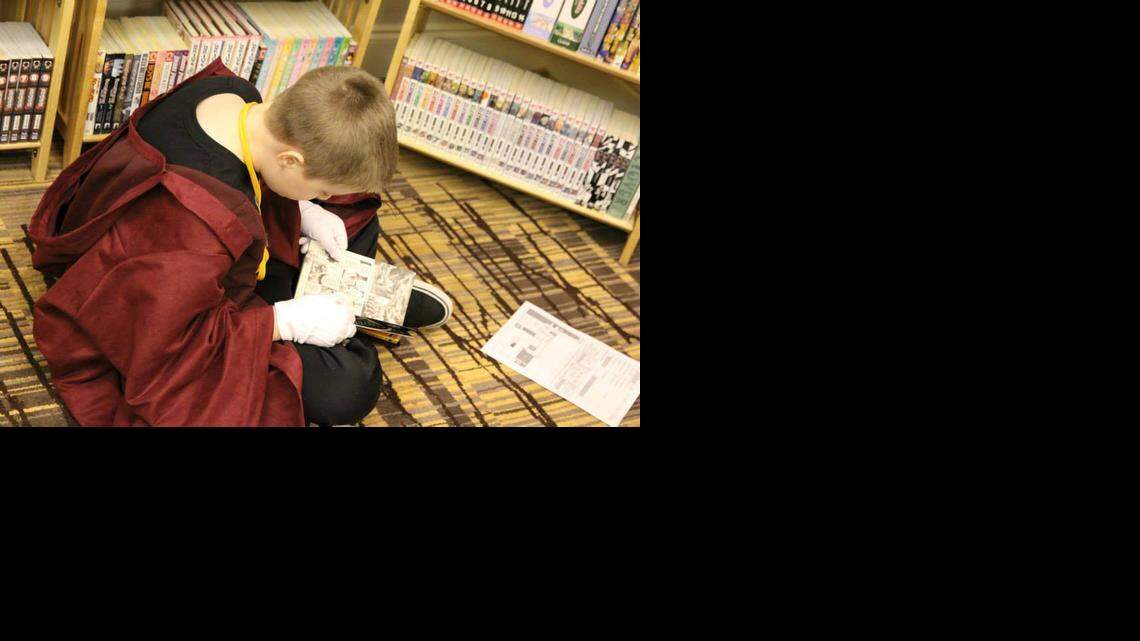 
A young fan reads manga provided by the Carolina Manga Library, which sets up its shelves filled with thousands of books at conventions around the country.
