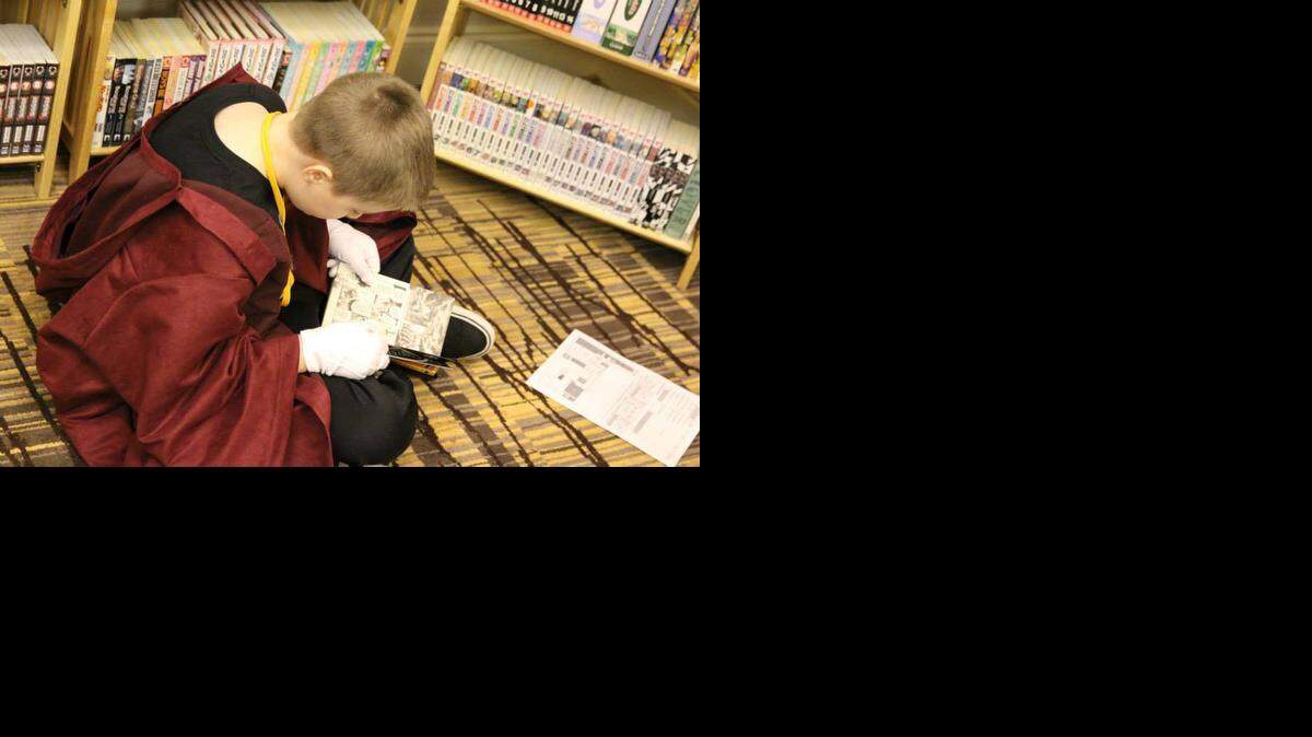 
A young fan reads manga provided by the Carolina Manga Library, which sets up its shelves filled with thousands of books at conventions around the country.
