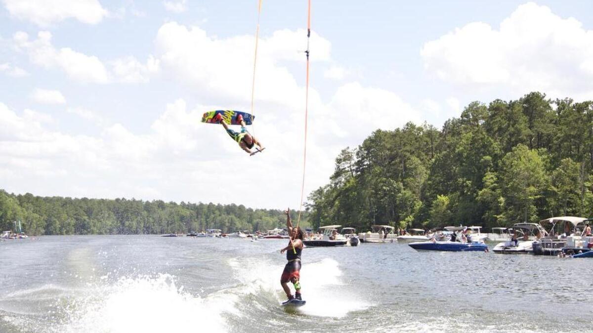 Professional wakeboarders Shaun Murray, airborne, and Josh Palma, on water, perform for a Lake Murray audience.