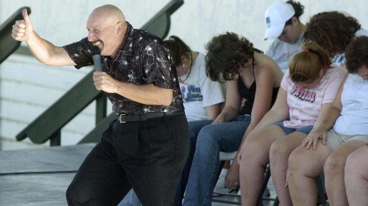 Ron Diamond gives the audience a thumbs-up as volunteers “sleep” behind him.