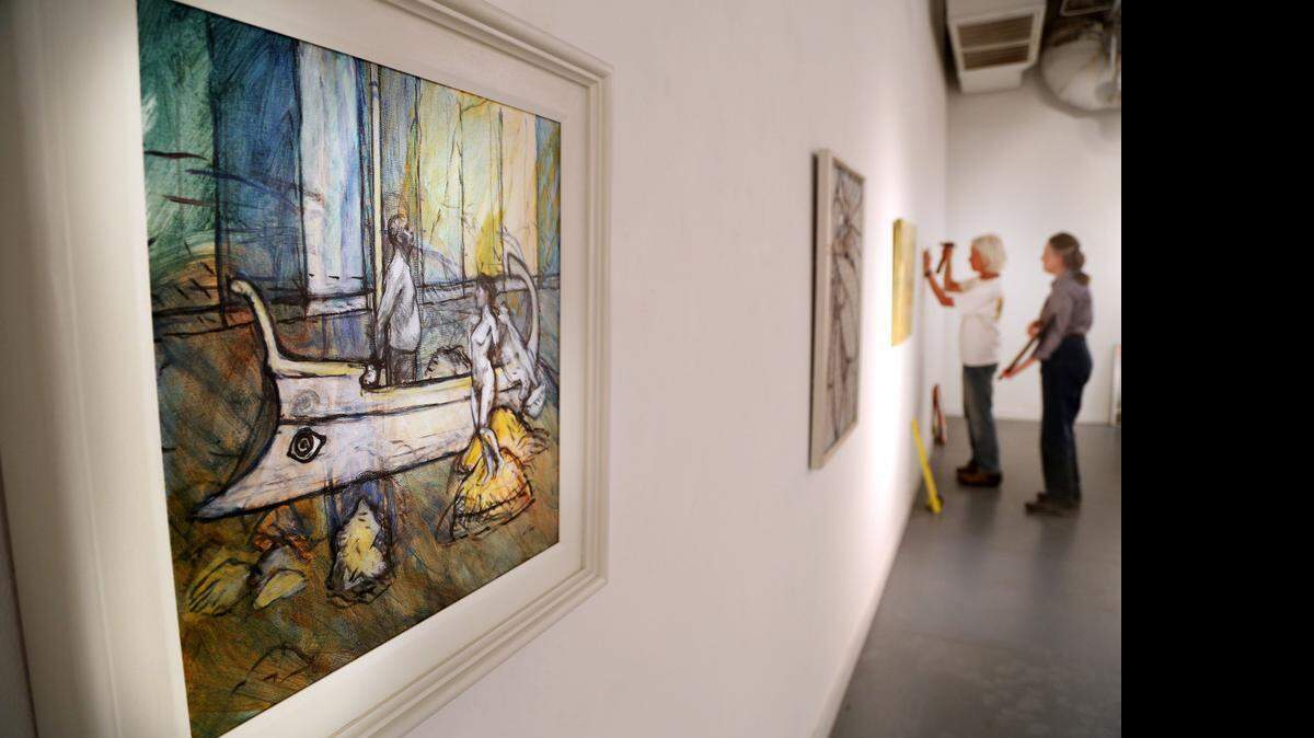 
David Yaghjian's oil painting “Odysseus” is pictured left as artists Eileen Blyth and Pat Gilmartin hang the rest of the pieces for Vista Studios/Gallery 80808's upcoming show “Gossip.”
