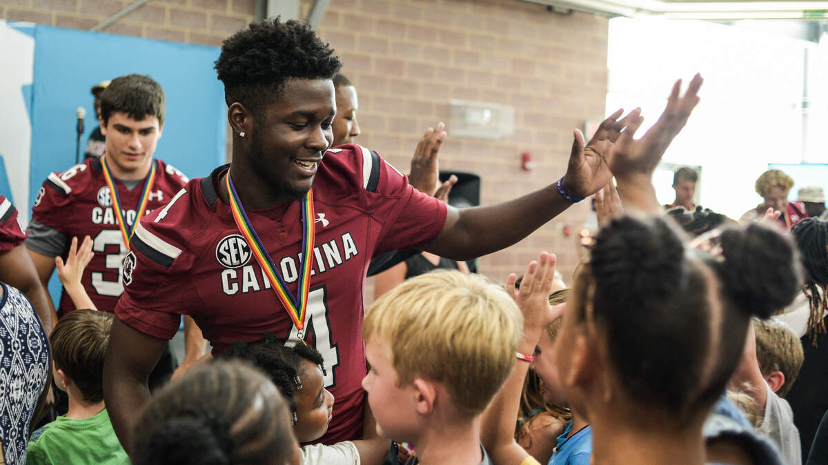 Darius Douglas (4) greets kids attending last year’s Pigskin Poets event at Drew Wellness Center.