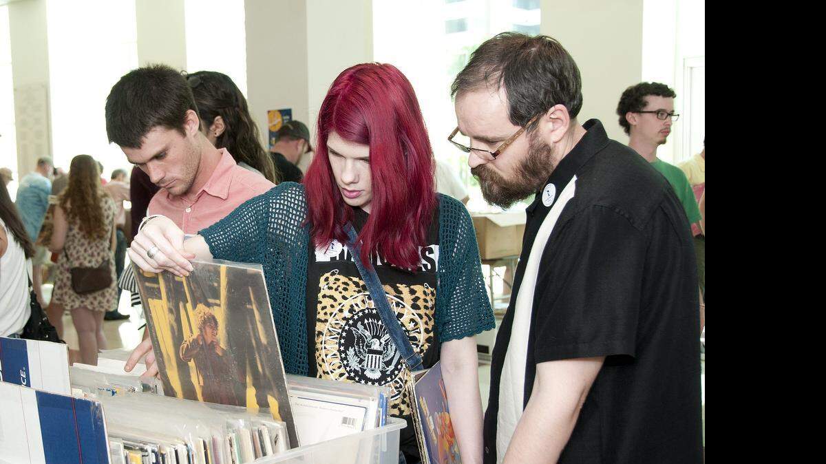 
Vinyl lovers, from left, Zak Pearsall, Gwen and Will Wood, search through vinyl albums at the Columbia Museum of Art during the 2014 Annual Columbia Record Fair. Pearsall bought Cars and B-52 albums. He said that his parents had good records and he likes getting a 'hard copy' of music rather than getting free stuff online because it “feels more real.” 
