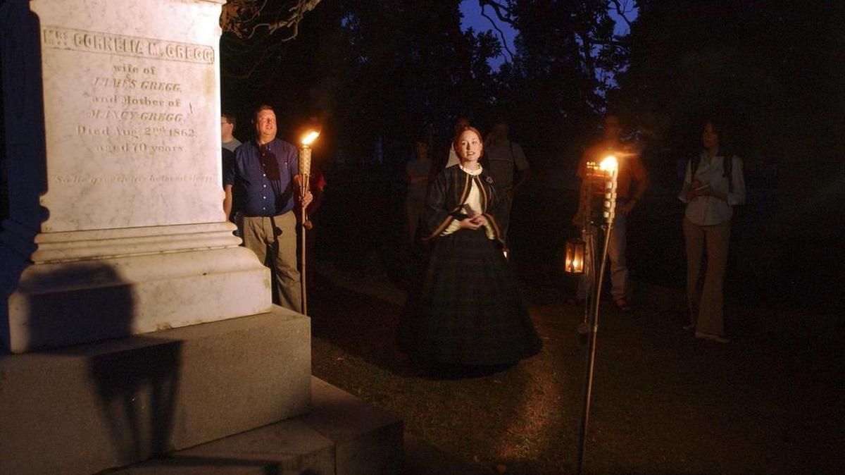 A tour guide tells a group about a grave during a tour of Elmwood Cemetery organized by Historic Columbia.
