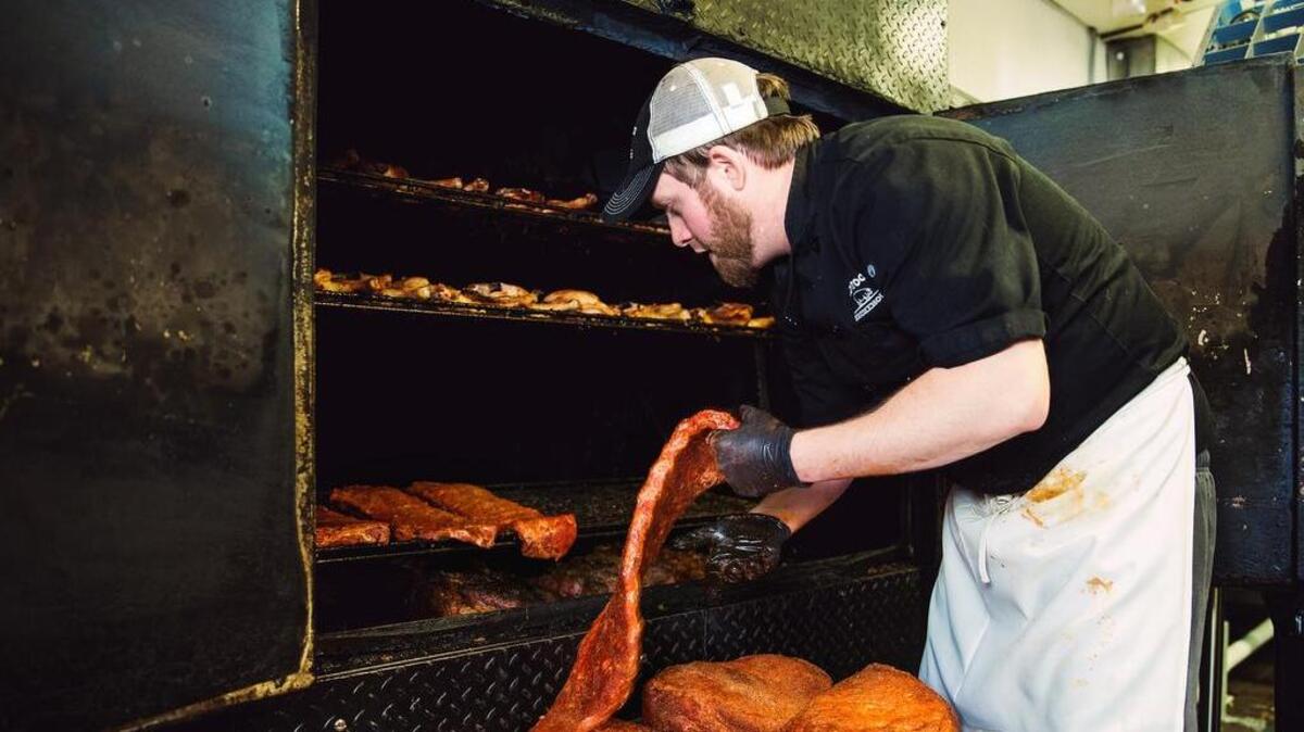 Pitmaster Matt Barry loads dry-rubbed St. Louis style pork ribs into the smoker at Midwood Smokehouse.