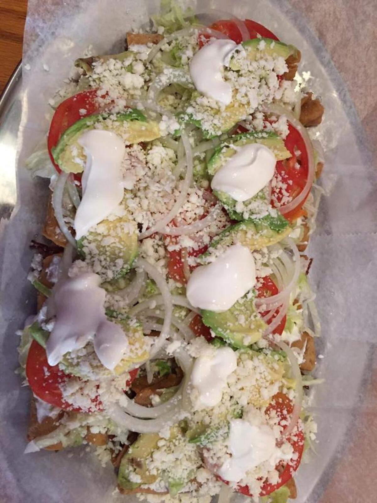 A flautas plate includes three 10-inch tortillas stuffed with chicken or beef brisket, fried slowly, and topped with sour cream, a red or green homemade sauce, lettuce, tomatoes, and avocado slices. It’s served with a side of rice.