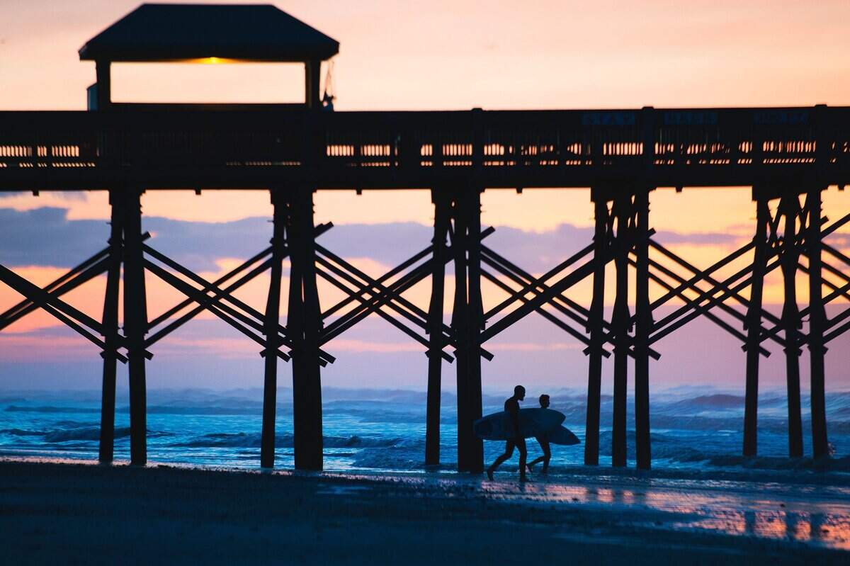 Surfers head out to the ocean from Folly Beach before the sun comes up.