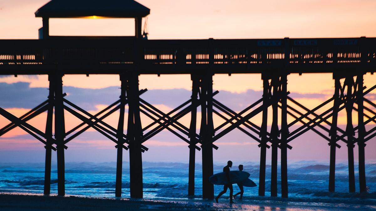 Surfers head out to the ocean from Folly Beach before the sun comes up.