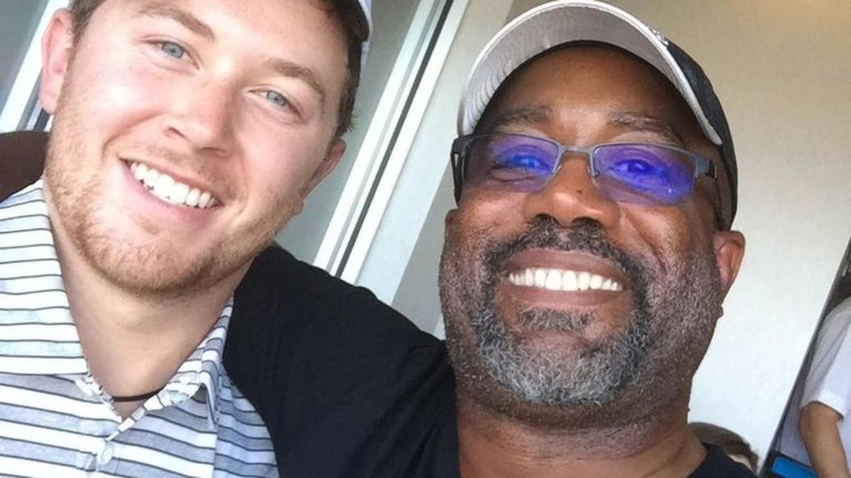 Darius Rucker, right, and Scotty McCreery engaged in some Twitter trash talk about the N.C. State vs. South Carolina football game before watching it together from a box on Saturday.