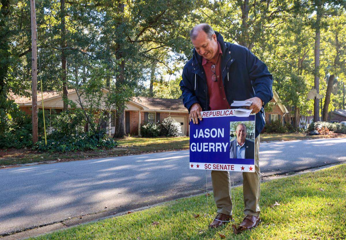 Republican candidate for Senate district 26, Jason Guerry places a sign while campaigning in the Whitehall neighborhood on Friday, Oct. 18, 2024