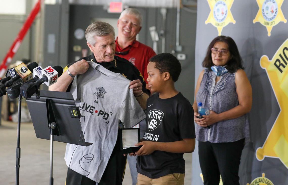 Richland County Sheriff Leon Lott presents Corval Reynolds, 10, with a Live PD T-shirt and a Sheriff’s Award for Community Service. Reynolds first heard a dog named Maxine, whimpering from inside a drainpipe and alerted his mother who called 911. 5/18/20