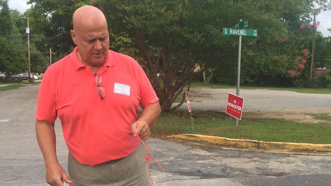 Poll worker Richard Schultz measures the distance between the entrance to Rosewood Elementary and campaign signs during the June 26, 2018 runoff election.