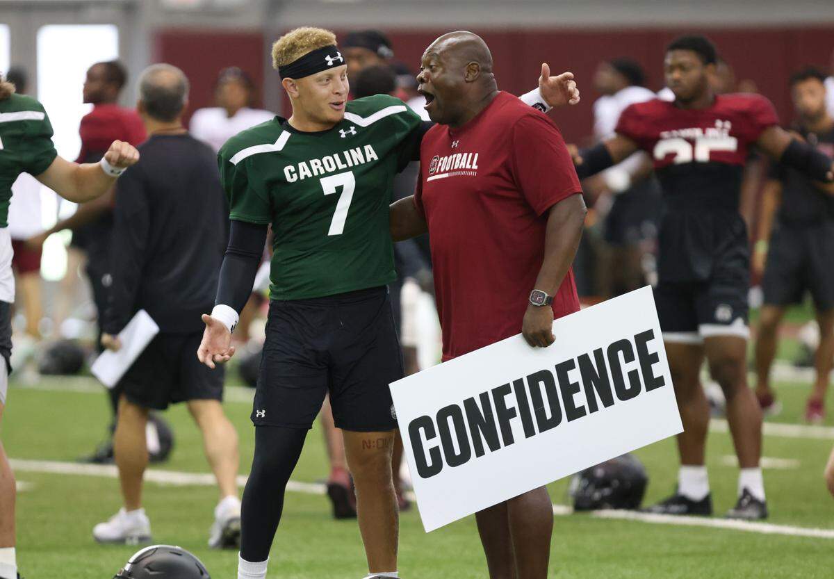 South Carolina quarterback Spencer Rattler (7) laughs with Executive Director of Character and Player Development Derrick Moore during practice in Columbia on Friday, August 11, 2023.
