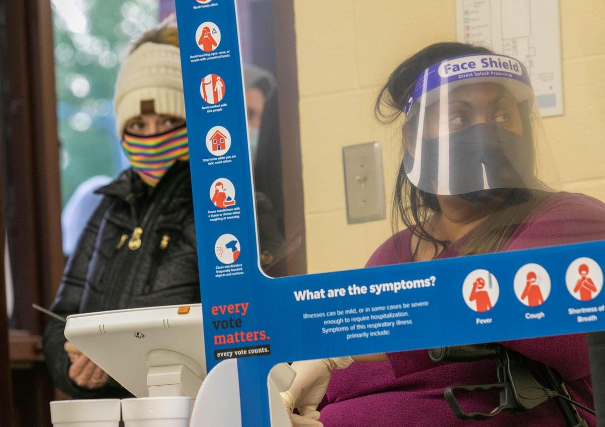 Poll worker Yvette Henry waits on a new machine to process a voter at the Woodlands Park precinct as Hilary Luna waits. Due to technical problems at the precinct, only 19 people had voted by 8 a.m. as hundreds of people waited outside to cast their votes on Tuesday, Nov. 3, 2020.