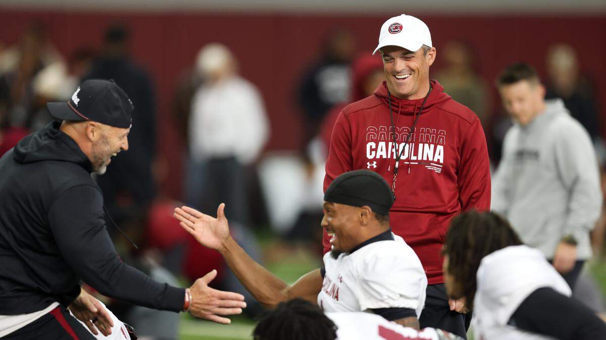 South Carolina head coach Shane Beamer laughs with passing game coordinator Mike Furrey and defensive back Gerald Kilgore (1) during a recent practice in Columbia 