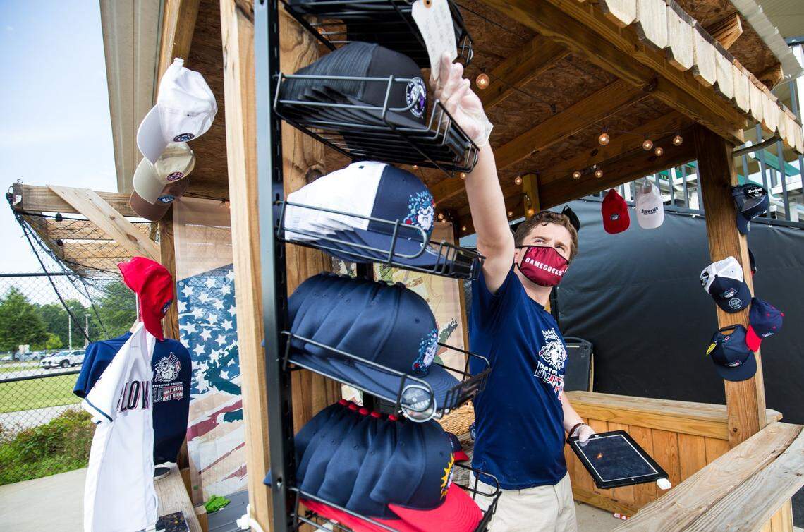 Lexington County Blowfish employee Tyler Tugwell helps a fan with a hat during the game against the Lake Murray Purple Martins. The Blowfish played with fans in the stands for the first time this season.