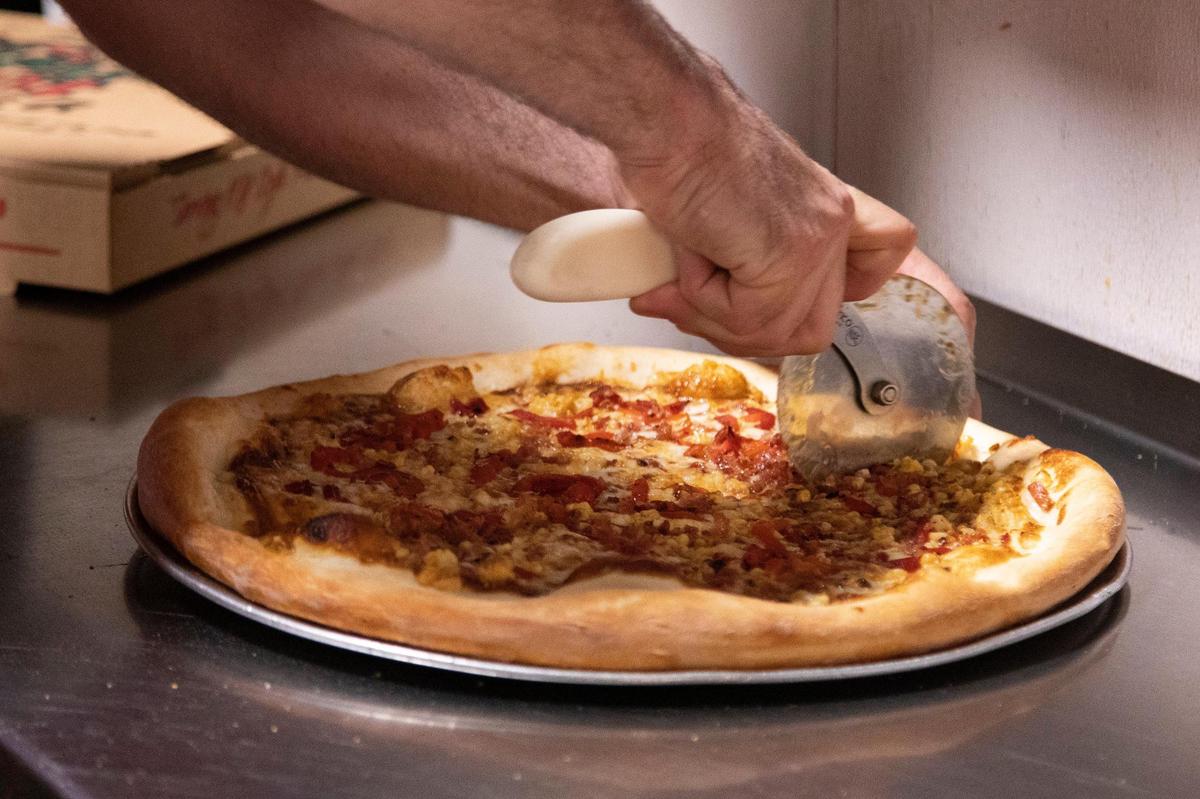 Brian Glynn cuts an elote pizza at Village Idiot Pizza in Five Points on Tuesday, April 26, 2022. The pizza will only be available in May.