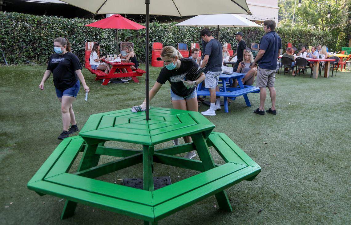 Elizabeth Manganello sanitizes a table at Publico in Columbia’s Five Points. The restaurant is one of many that opened up for outside seating after being forced to shut down to help prevent the spread of the coronavirus. Meals are served in disposable take-out containers and the wait staff wears protective masks and gloves. 5/5/20