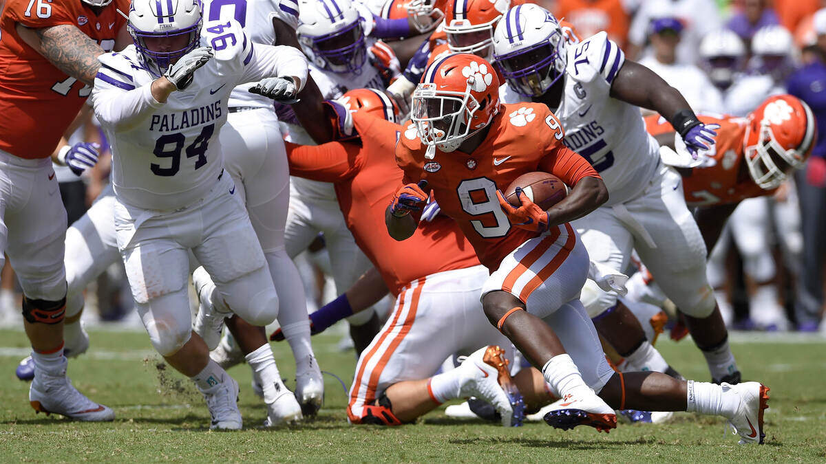 Clemson’s Travis Etienne rushes out of the backfield while pursued by Furman’s Jaylan Reid, 75, and Jonah Tibbs during the first half of an NCAA college football game Saturday, Sept. 1, 2018, in Clemson, S.C.