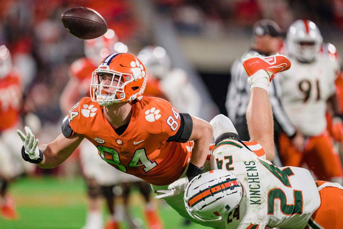 Miami safety Kamren Kinchens (24) forces a fumble by Clemson tight end Davis Allen (84) during the second half of an NCAA college football game Saturday, Nov. 19, 2022, in Clemson, S.C. (AP Photo/Jacob Kupferman)