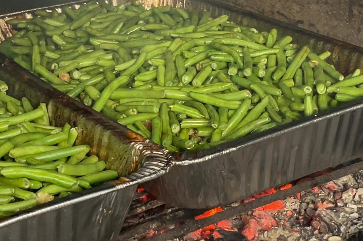 At City Limits Barbeque, pans of fresh green beans cook over hot coals in the smoker, underneath dripping pork belly. 