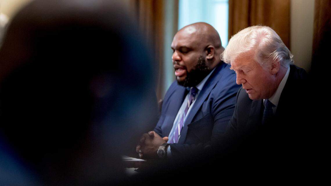 President Donald Trump, right, bows his head as Relentless Church Pastor John Gray, left, says a prayer during a meeting with inner city pastors in the Cabinet Room of the White House in Washington, Wednesday, Aug. 1, 2018.