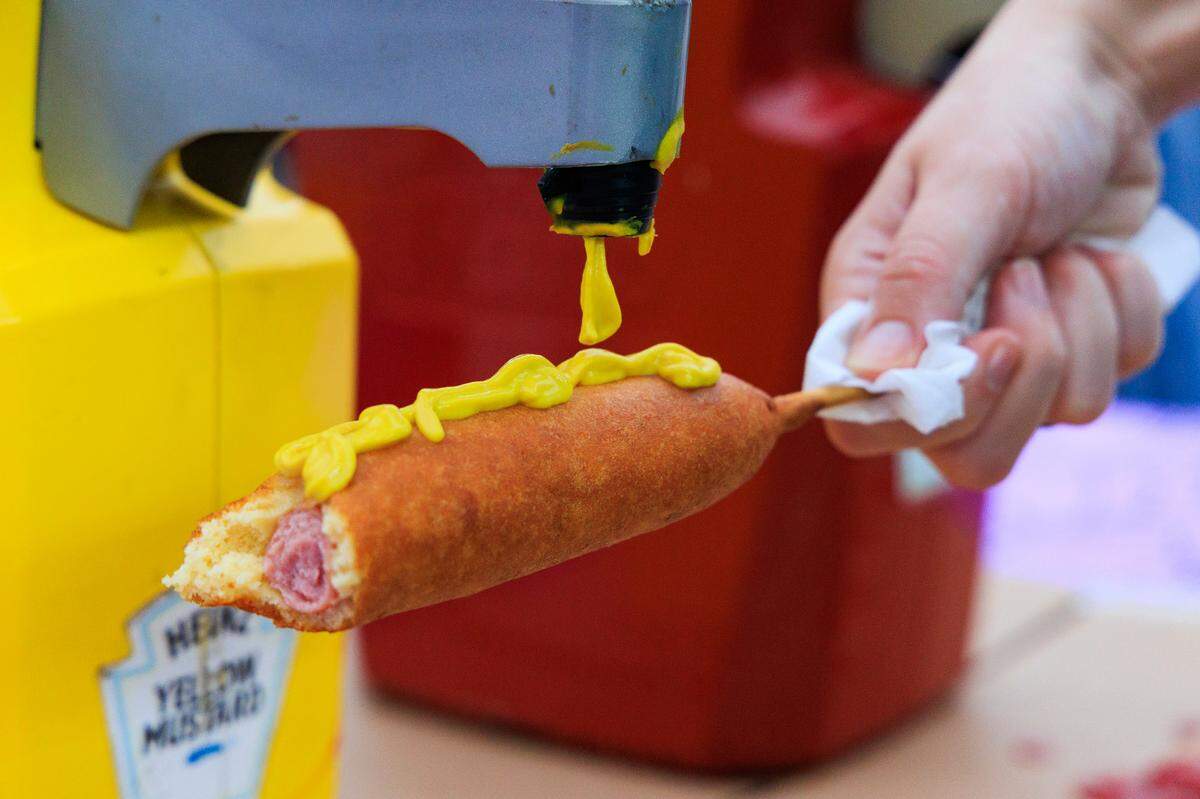 The State reporter Morgan Hughes puts mustard on a Pronto Pup during the opening day of the South Carolina State Fair on Wednesday, October 11, 2023. Pronto Pups are made with pancake batter instead of a cornmeal batter that more common corndogs use.