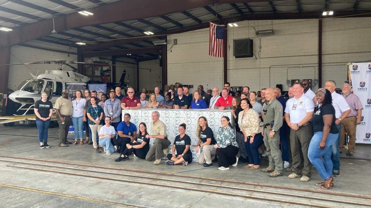 Community and law enforcement volunteers pose after assembling over 300 packages of food for the Greg’s Groceries initiative.