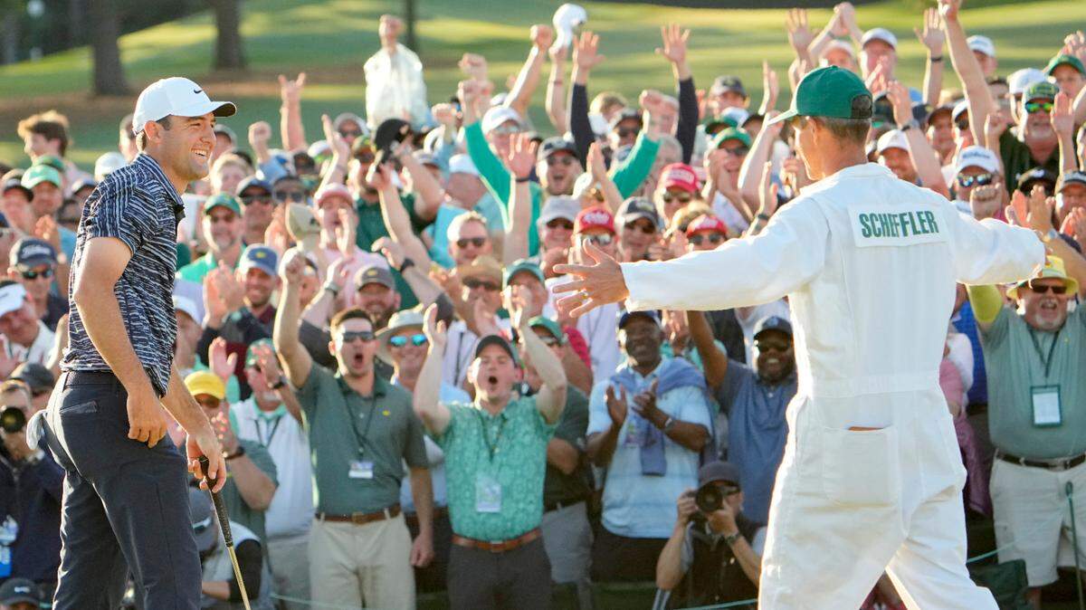 Scottie Scheffler celebrates with his caddie, Ted Scott, after finishing his round on no. 18 during the final round of the 2022 Masters Tournament at Augusta National Golf Club.