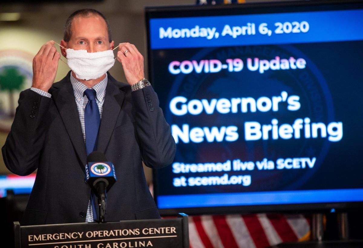 Nicholas Davidson, Acting Director of Public Health of DHEC, demonstrates how to use a cloth as a face mask during a press conference at the South Carolina Emergency Operations Center.