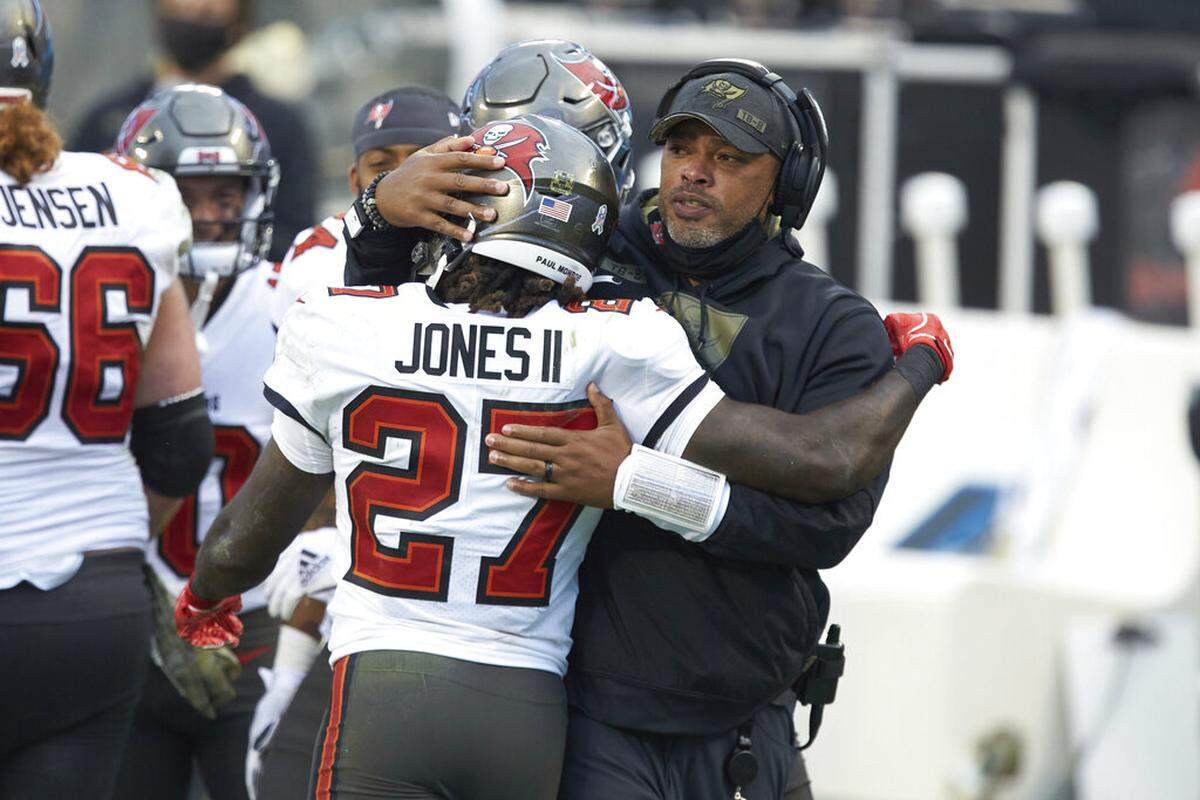 Tampa Bay Buccaneers running back Ronald Jones II (27) gets a hug from assistant head coach Harold Goodwin during an NFL football game against the Carolina Panthers, Sunday, Nov. 15, 2020, in Charlotte, N.C.