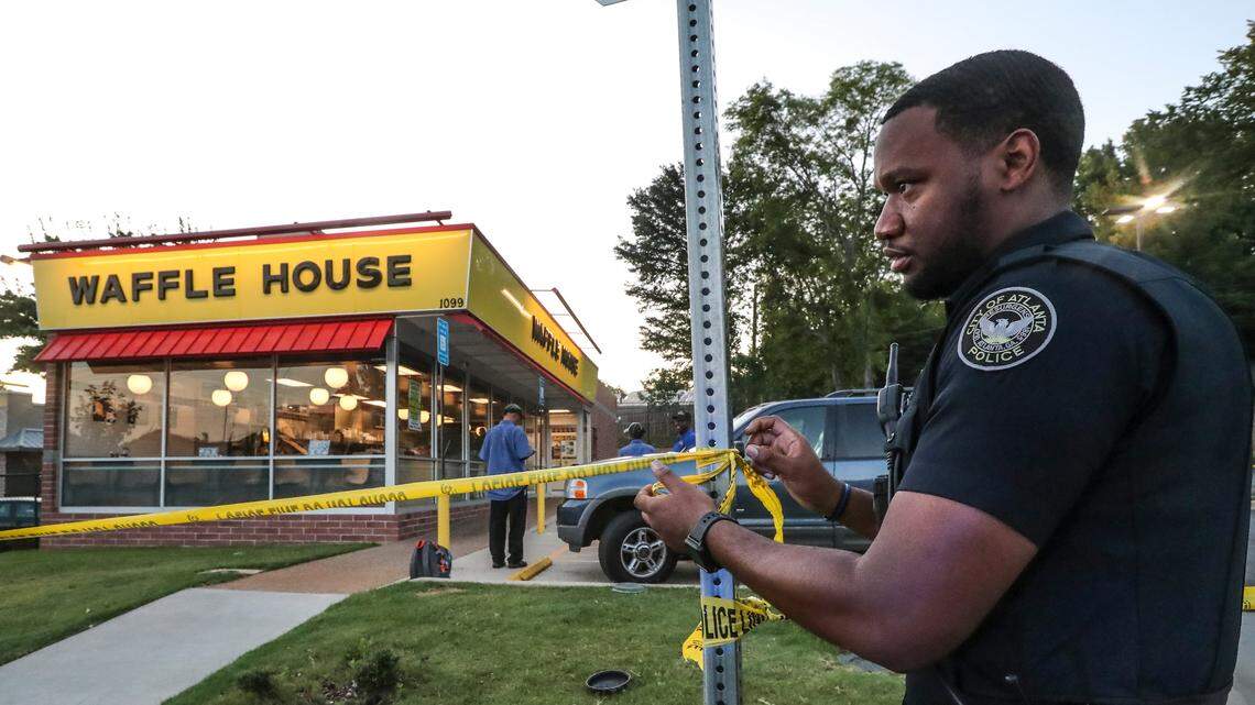 Atlanta Police Officer T. Williams secures the crime scene of a shooting at a Waffle House, Tuesday, July 10, 2018 in Atlanta.  Police say a man described as wearing an "angry clown mask" shot a customer at a Waffle House in Atlanta.