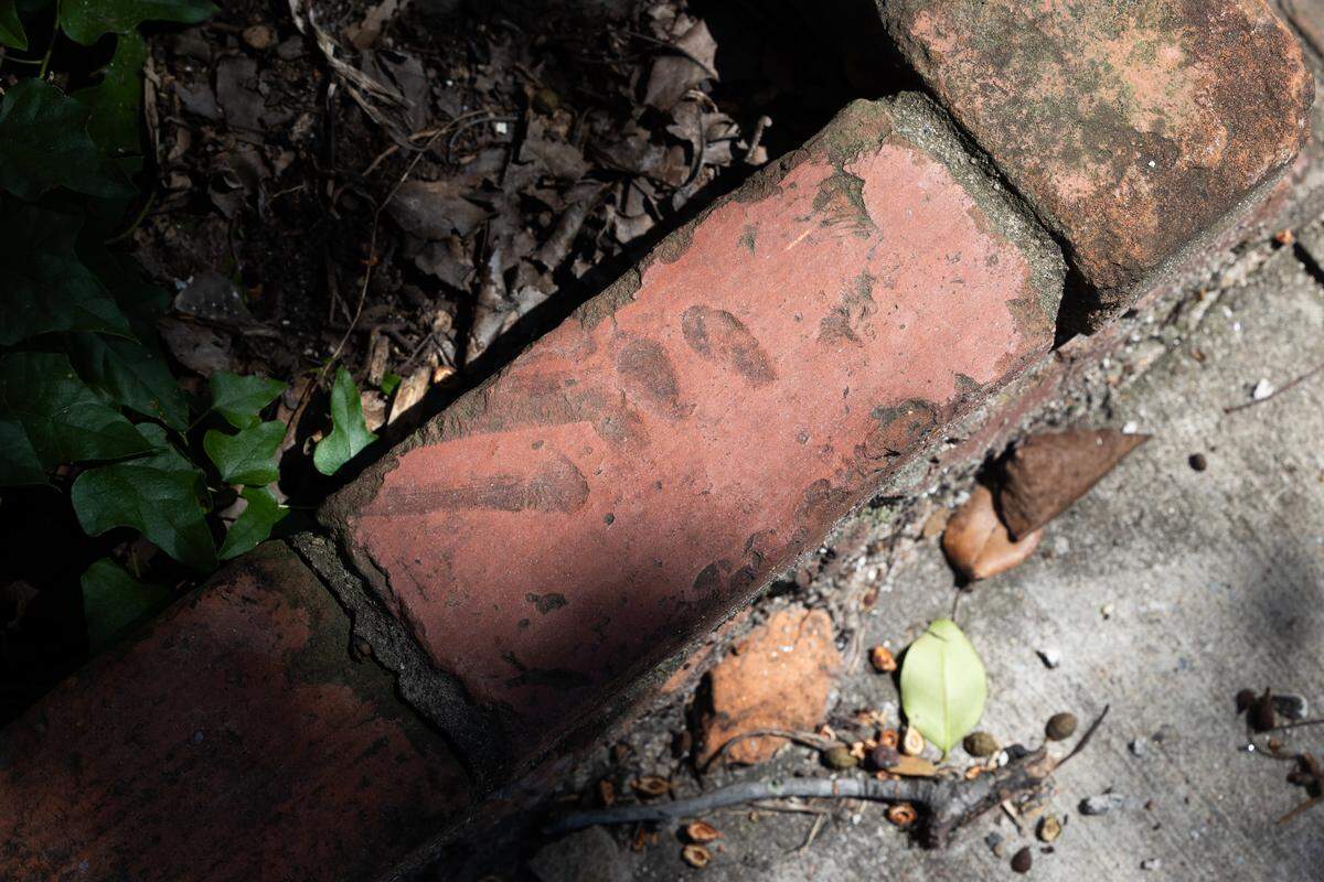 A brick with the fingerprints of the person who originally fired the brick lines a garden outside the Hunter-Gartherer location on South Main Street in Columbia, South Carolina on Saturday, June 28, 2025. Teams of volunteers assisted organizing pieces of the building for resale, and helped preserving the mural of Aaron Graves, a local musician who died of cancer in 2019. 