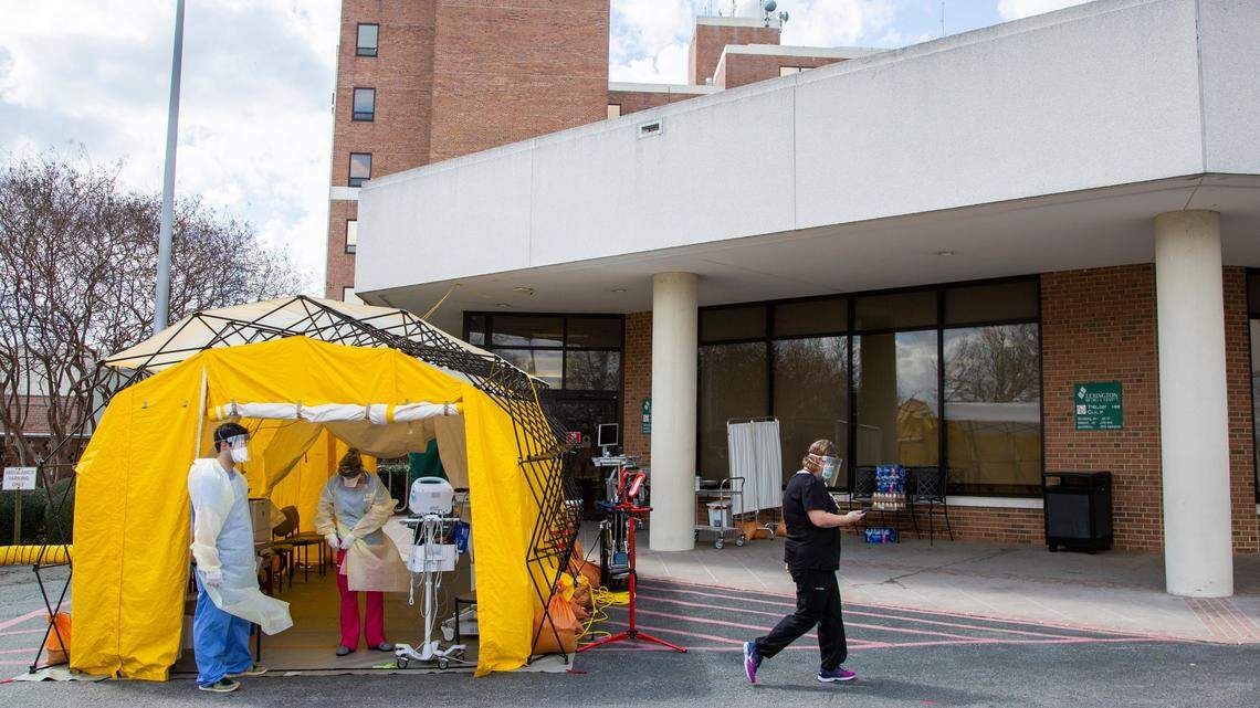 Doctors wait in a yellow tent that is serving as an addition triage area outside of Lexington Medical Center on Wednesday, March 11, 2020. If patients walk up to the ER with respiratory symptoms, they are given a mask and directed to the yellow tent. They are then screened, and taken through a separate entrance so they will not come in contact with anyone seeking treatment for other ailments.