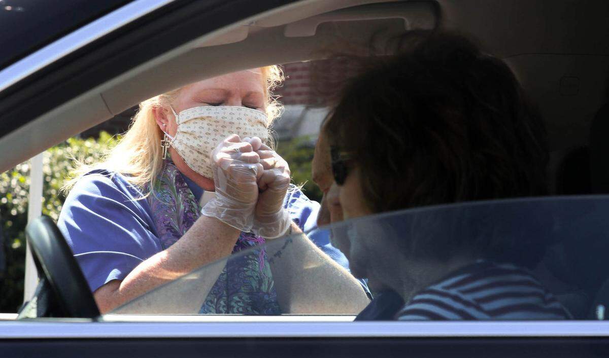 The Rev. Gina Metze prays with Wayne and Marcia Wadford after offering them communion in their car. While the coronavirus prevented gathering in church for Holy Week, the church provided three opportunities for communion and drive-up blessings in addition to live streaming services and having a nightly online prayer.