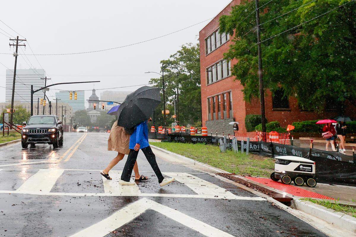 Students and a Grubhub delivery robot cross Main Street as Hurricane Helene hits Columbia, South Carolina on Thursday, September 26, 2024.