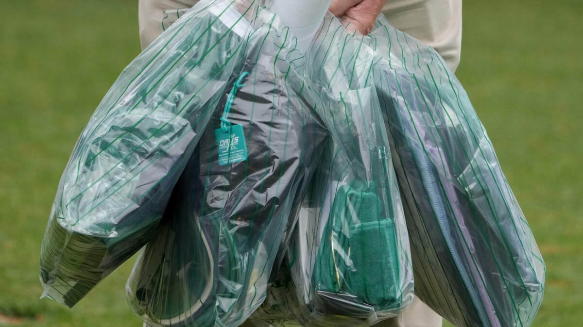 A patron carries bags of merchandise from the golf shop on No. 14 during a practice round Tuesday for The Masters golf tournament at Augusta National Golf Club.