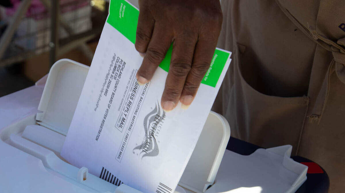 A poll worker places a mail-in absentee ballot in a secure box outside the Richland County Voter Registration office on Monday, Nov. 2, 2020.