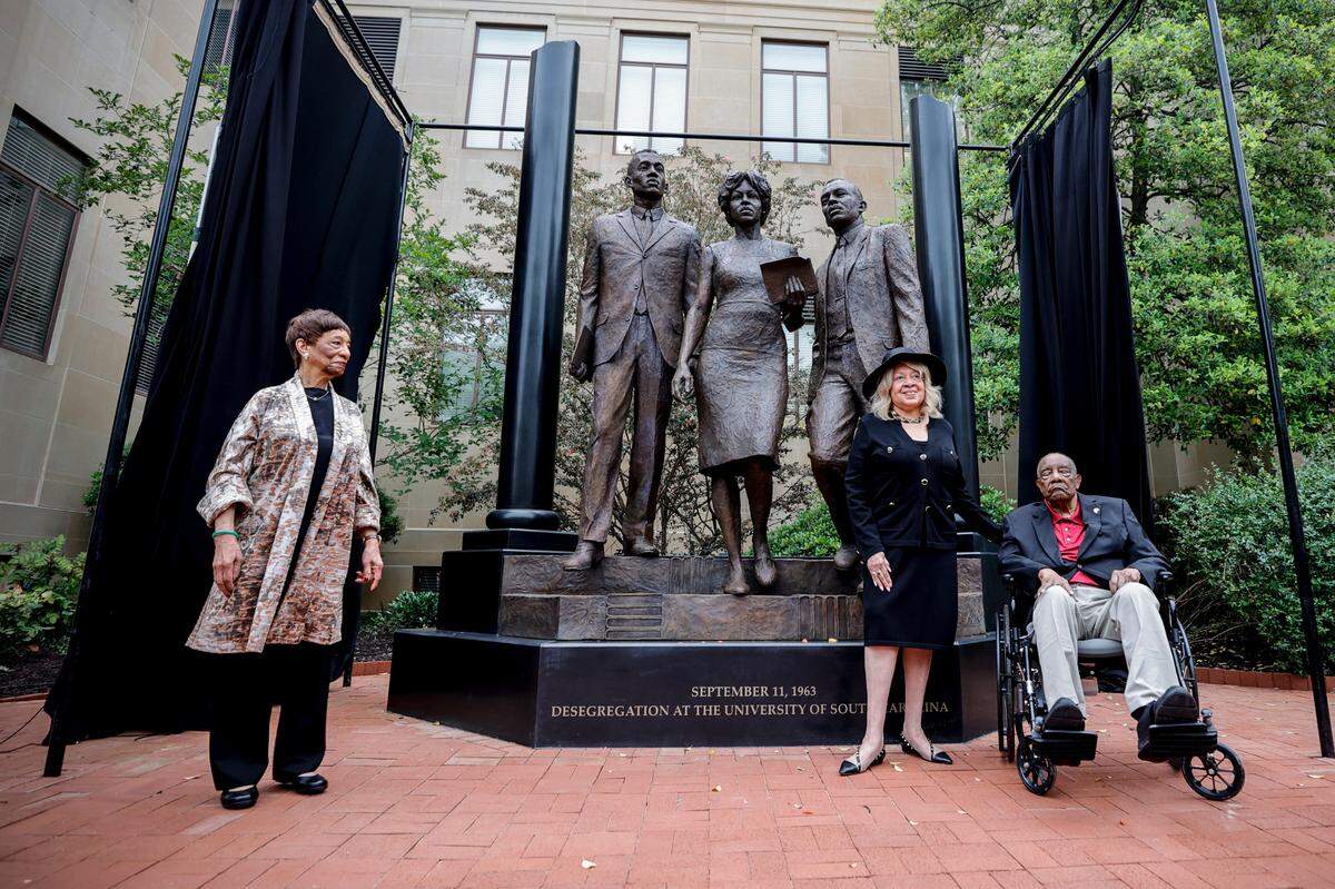 Carmen Smith, Henrie Monteith Treadwell and James Solomon Jr. pose in front of the new desegregation monument at The University of South Carolina. The monument, which was unveiled on Friday, April 19, 2024, was created from a photograph showing Treadwell, Solomon and Robert Anderson as the first Black students admitted to the university. Carmen Smith is Robert Anderson’s sister.