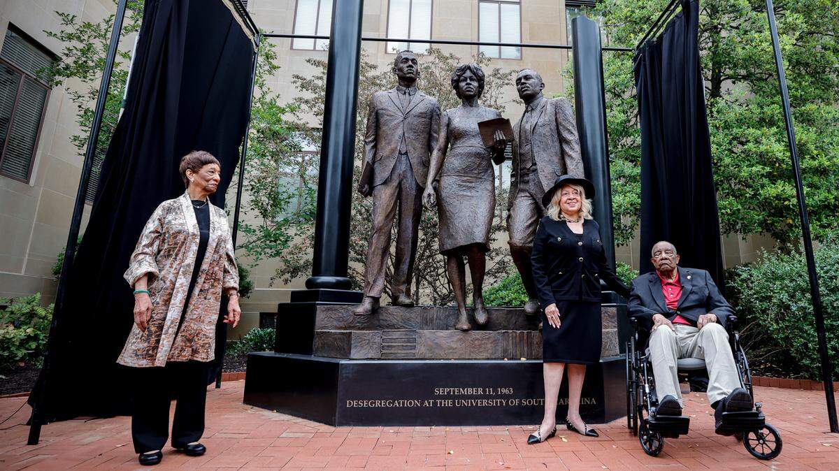 Carmen Smith, Henrie Monteith Treadwell and James Solomon Jr. pose in front of the desegregation monument at the University of South Carolina that was created from a photograph showing Treadwell, Solomon and Robert Anderson as the first Black students admitted to the university. Carmen Smith is Robert Anderson’s sister.