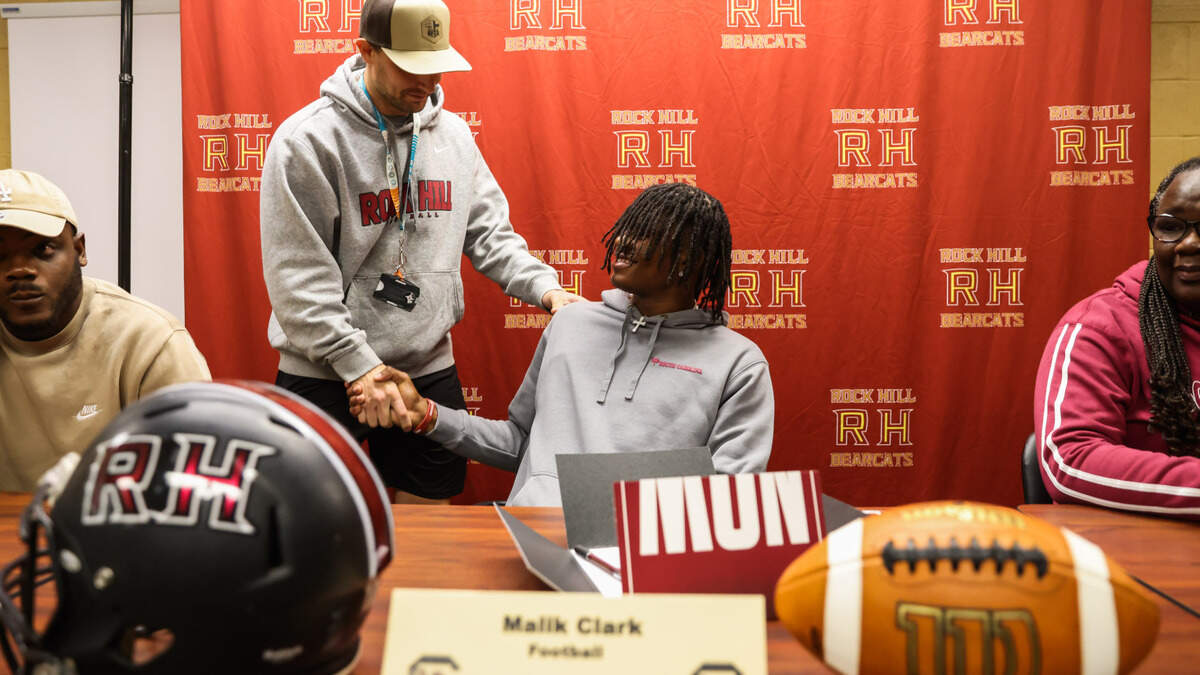 Malik Clark, a wide receiver from Rock Hill High School, shakes hands with wide receiver coach Tyler Klipa, during a signing day ceremony at his school on Wednesday, December 4, 2024.