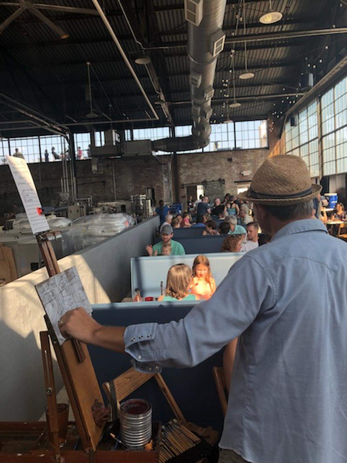 Artist Trahern Cook paints as part of Leah McCleskey’s fundraiser at Hunter Gatherer brewery at the Curtiss Wright Hangar.