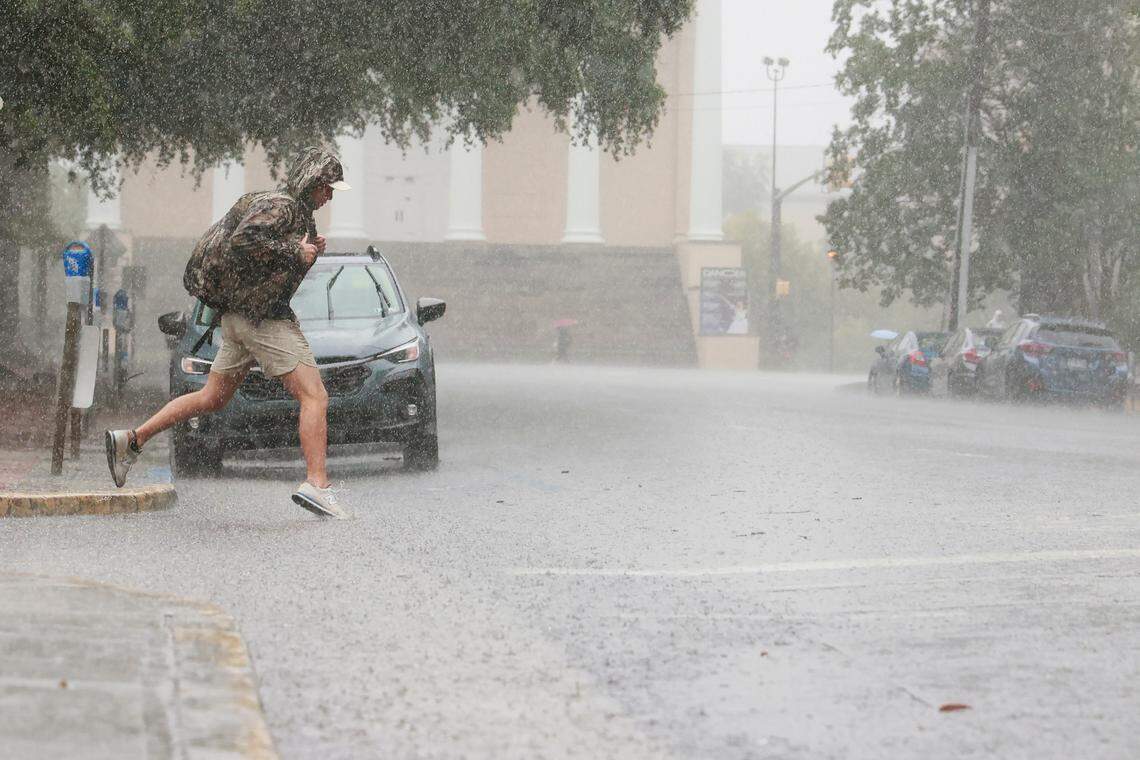 A University of South Carolina student attempts to leap over a wide and deep puddle as Hurricane Helene hits Columbia, South Carolina on Thursday, September 26, 2024.