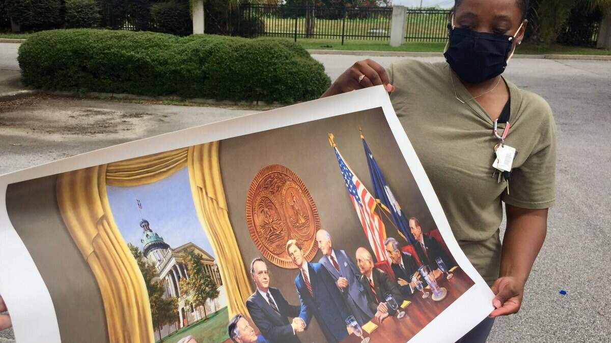 Teidra Whiteside holds a painting depicting a reunion of S.C. governors, which was found in a storage unit containing items belonging to the late Gov. Carroll Campbell.