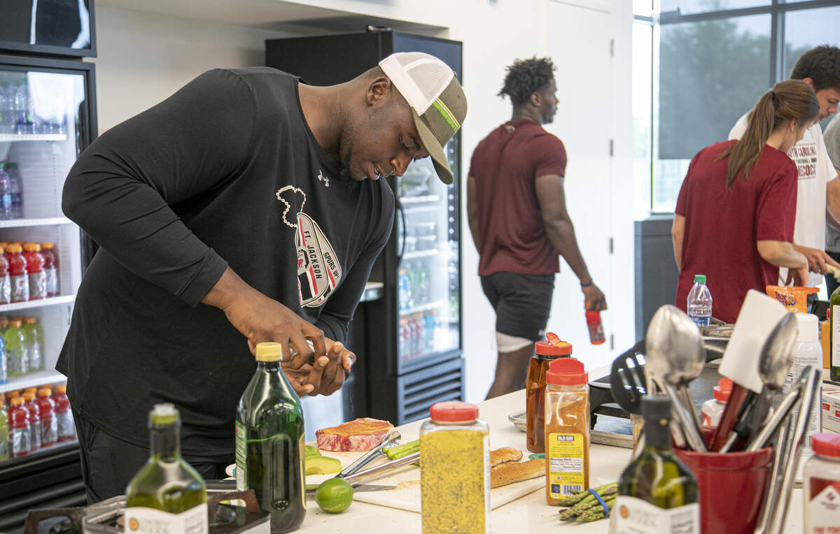 Donell Stanley seasons a steak he is preparing to cook.